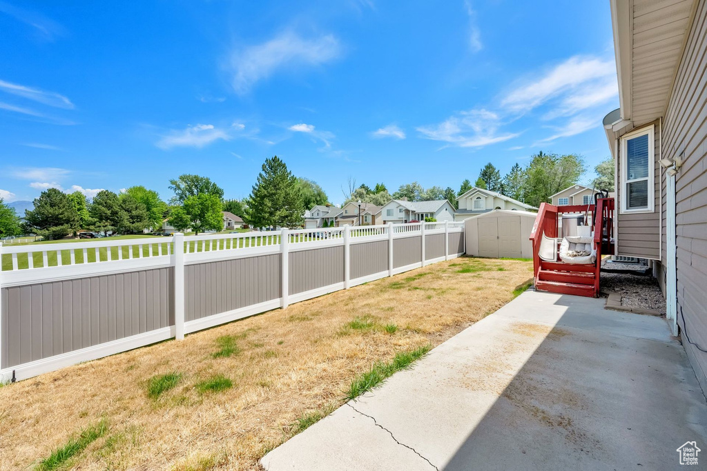 Fenced backyard with a storage unit, a patio, and a residential view
