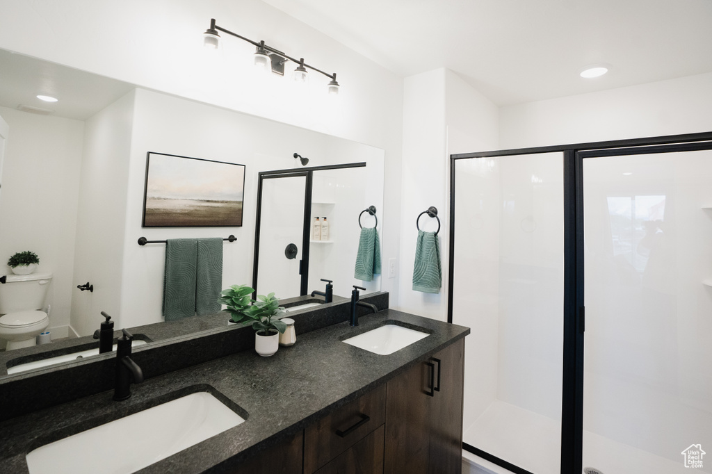 Full bath with a shower stall, double vanity, and recessed lighting