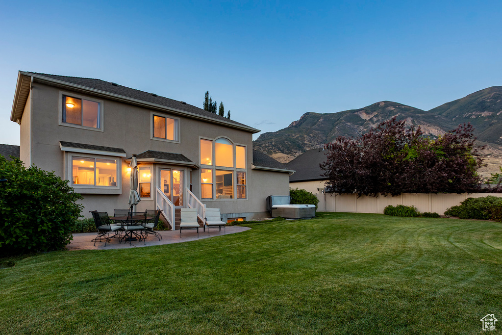 Rear view of property featuring stucco siding, a patio area, and a yard