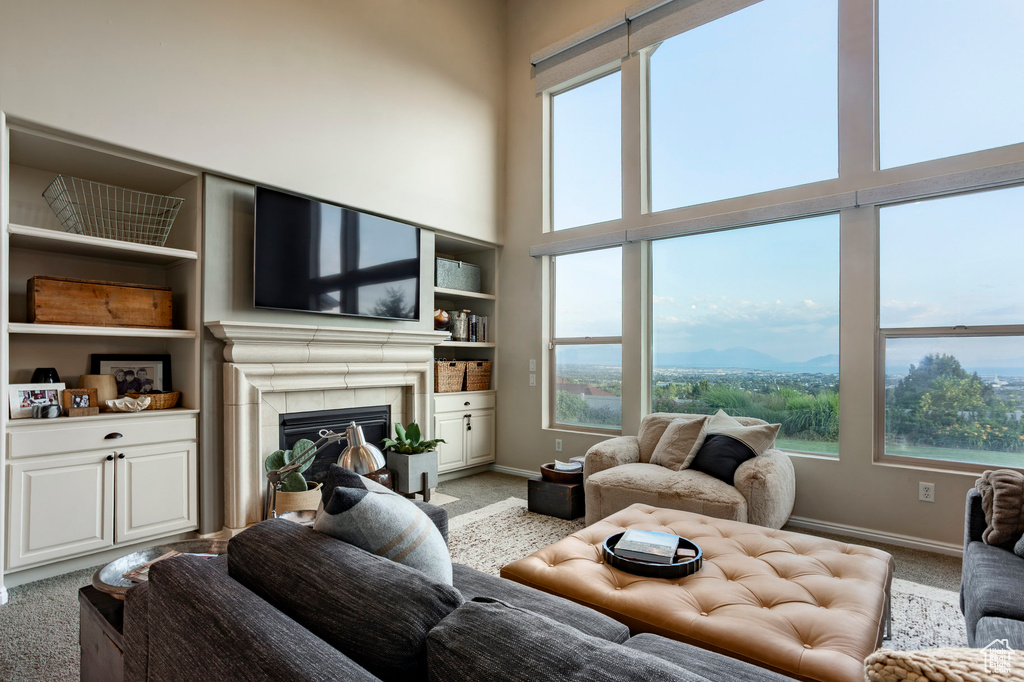 Living room with light colored carpet, a glass covered fireplace, and a towering ceiling