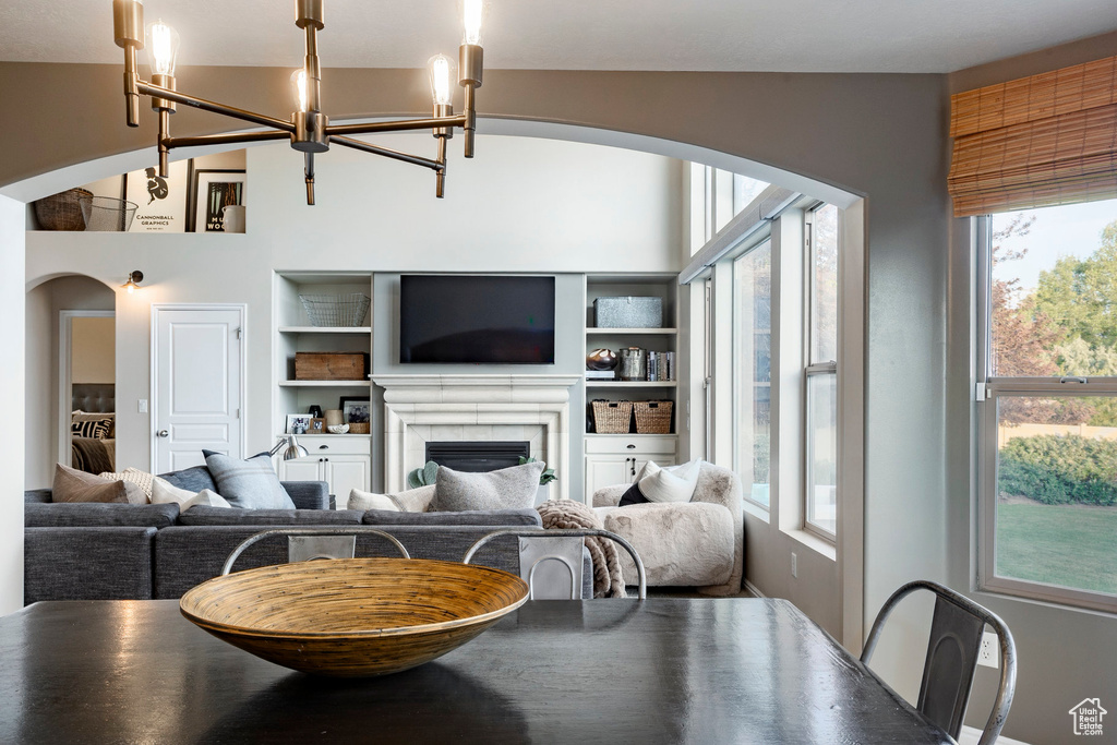 Living area with arched walkways, a chandelier, a fireplace, and built in features