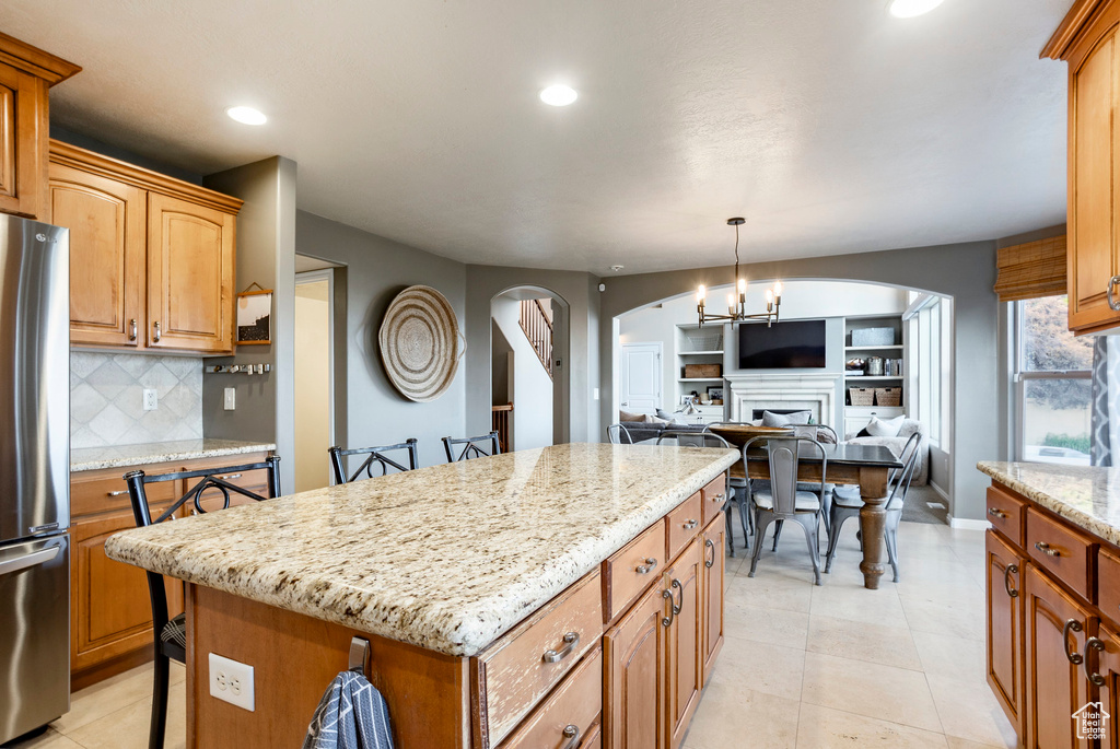 Kitchen with freestanding refrigerator, arched walkways, recessed lighting, open floor plan, and decorative backsplash