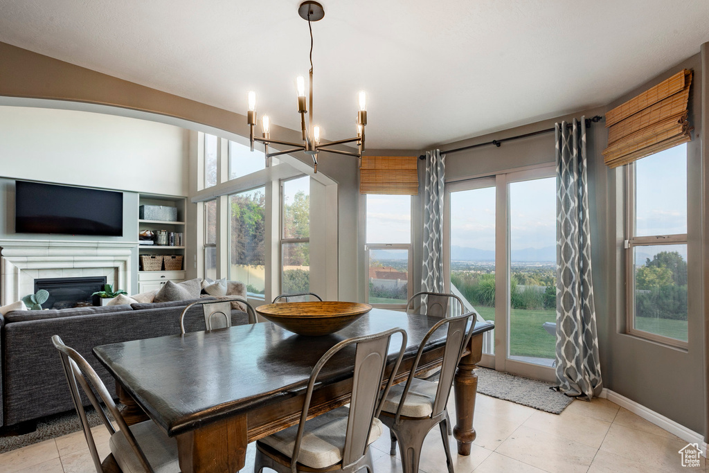Dining area featuring a chandelier, healthy amount of natural light, a fireplace, and light tile patterned flooring