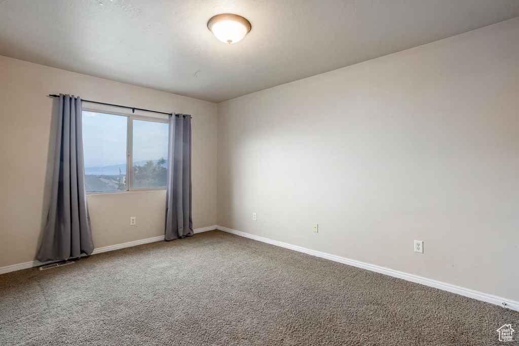Carpeted spare room with baseboards