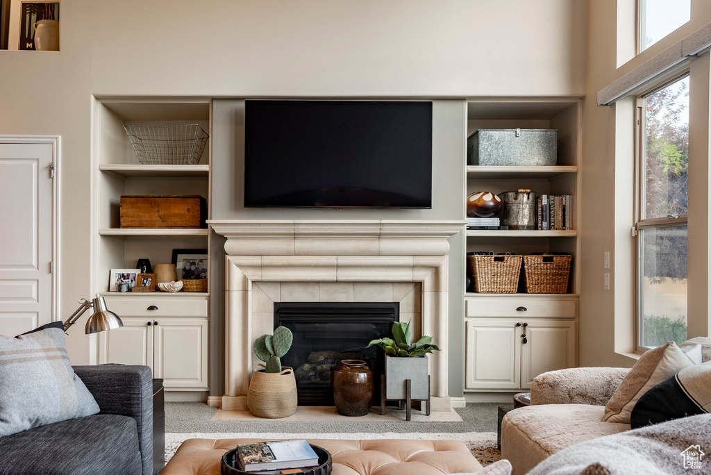 Carpeted living room featuring built in features and a tiled fireplace