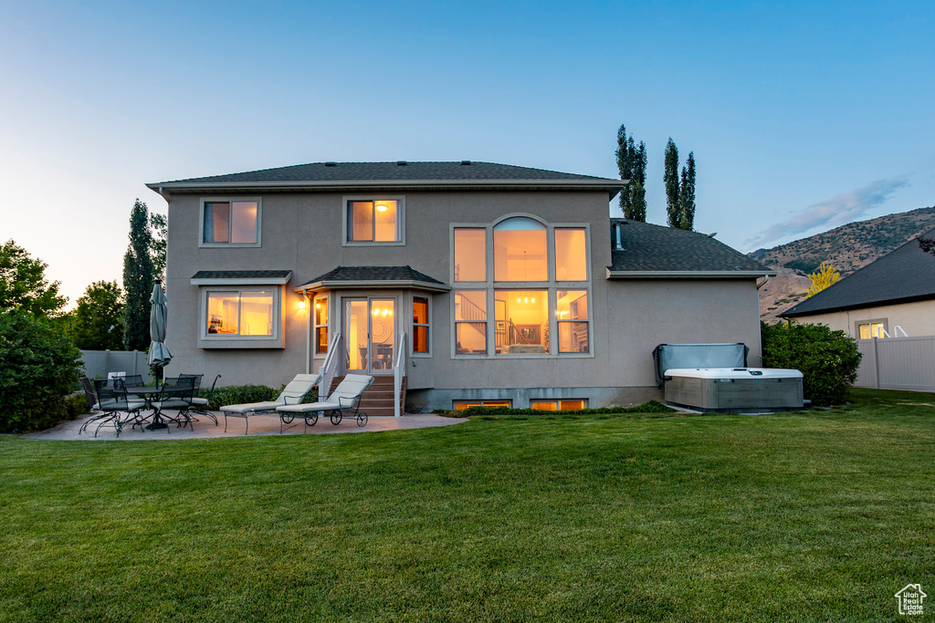 Back of house featuring a hot tub, stucco siding, a patio, entry steps, and roof with shingles
