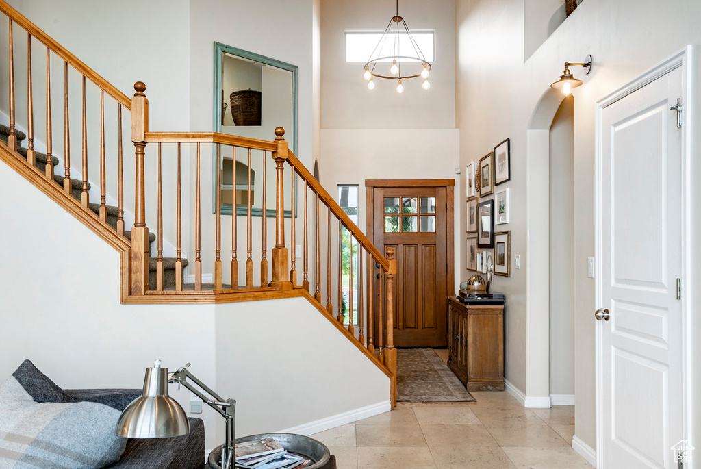Foyer entrance with a high ceiling, stairs, a chandelier, and arched walkways