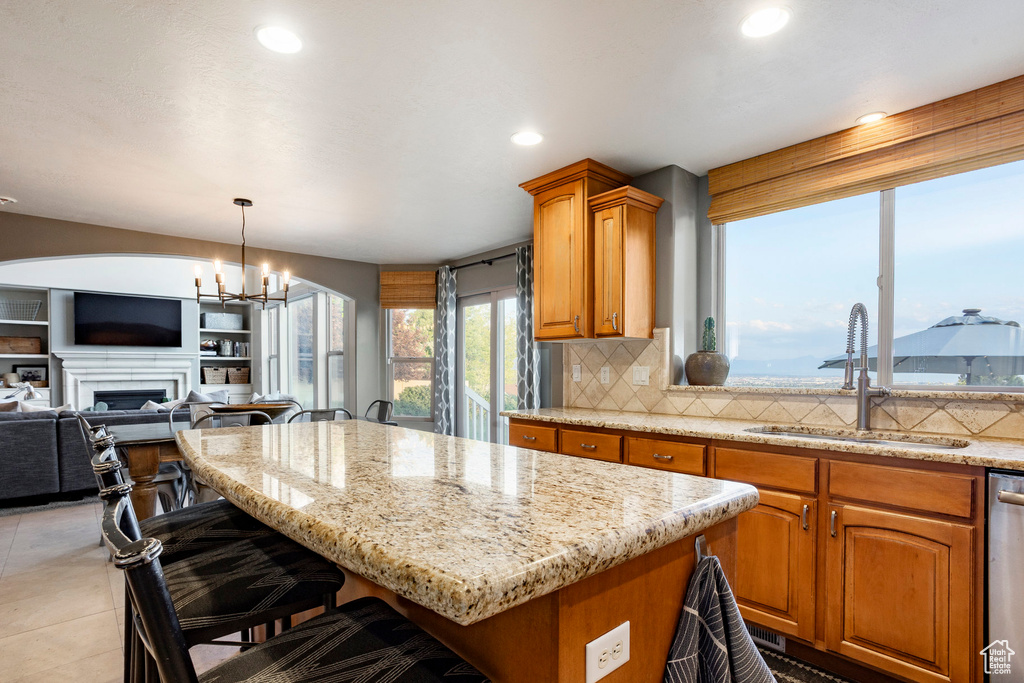 Kitchen with a kitchen island, backsplash, a kitchen bar, light stone countertops, and a chandelier