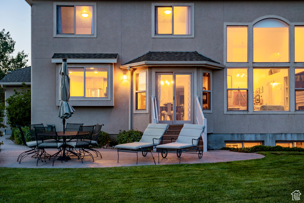 Rear view of property with a patio area, a lawn, and stucco siding