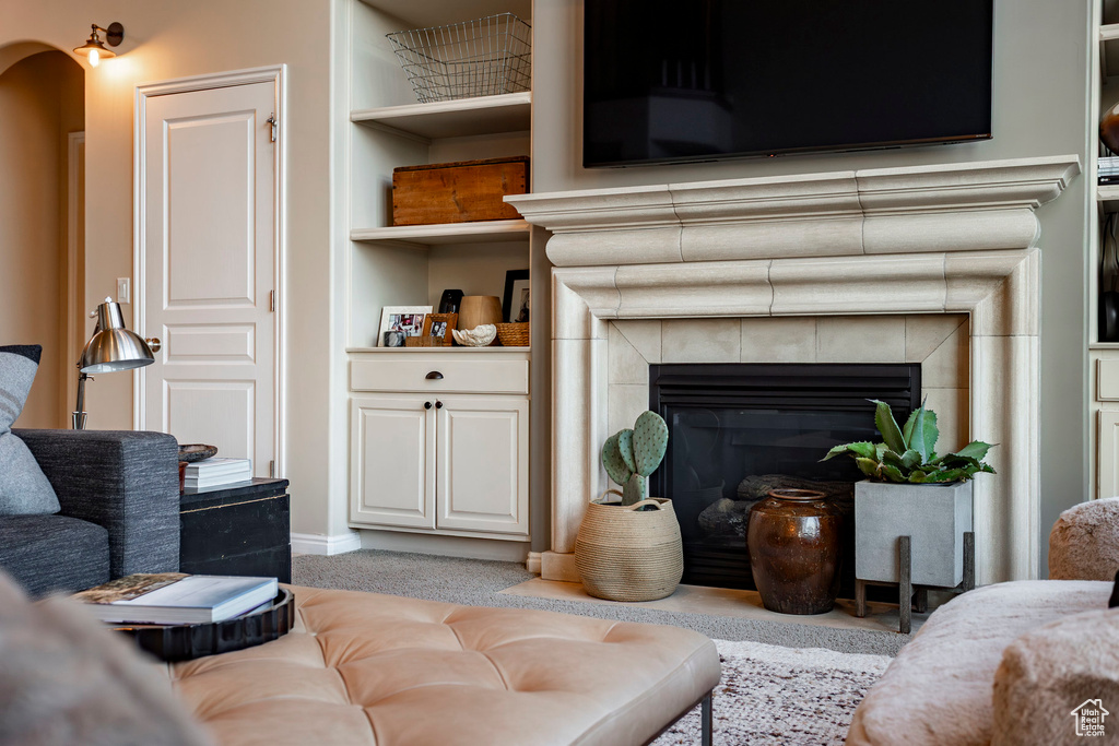 Carpeted living room with a fireplace, built in shelves, and arched walkways