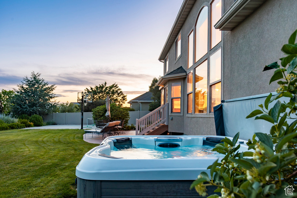 Yard at dusk featuring a hot tub and a patio area
