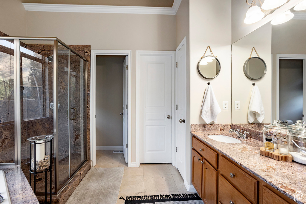 Full bathroom featuring crown molding, vanity, a stall shower, and tile patterned floors