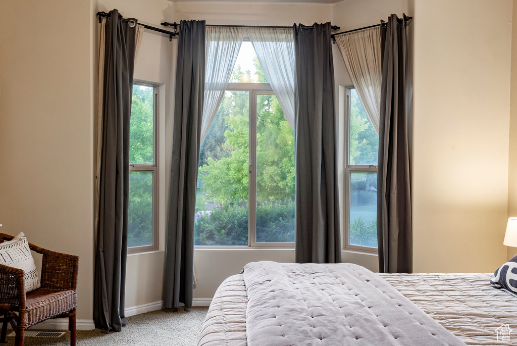 Bedroom featuring light colored carpet and multiple windows