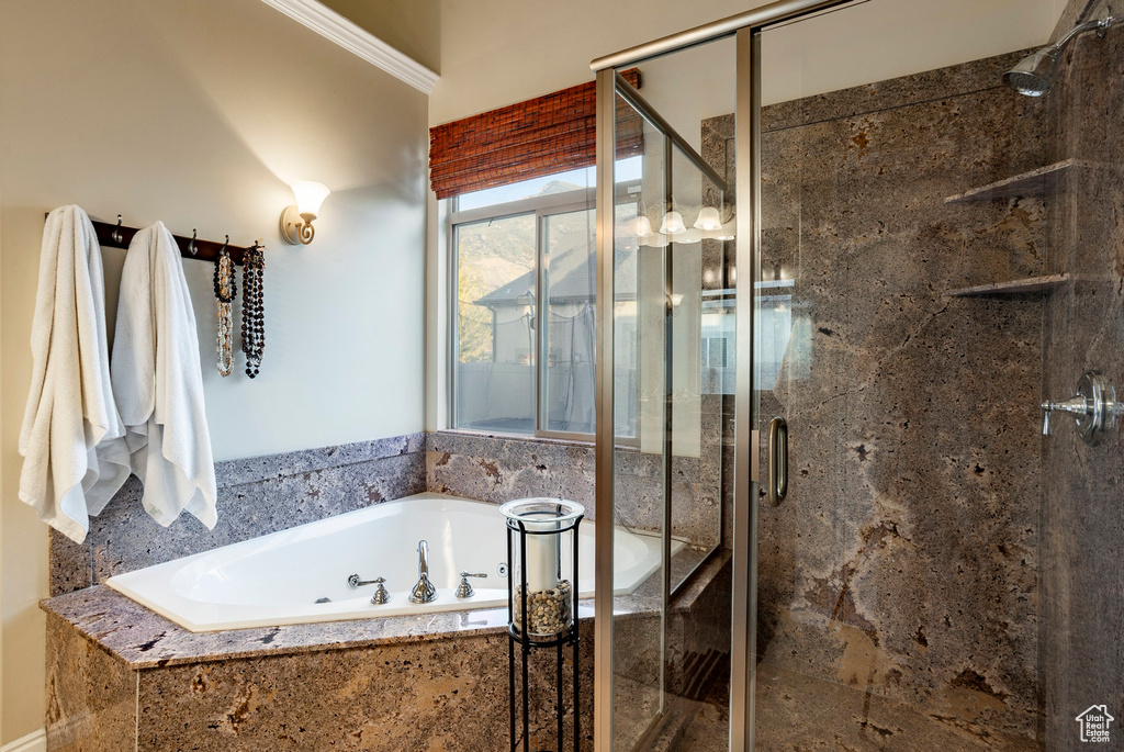 Full bathroom featuring a shower stall, a garden tub, and crown molding