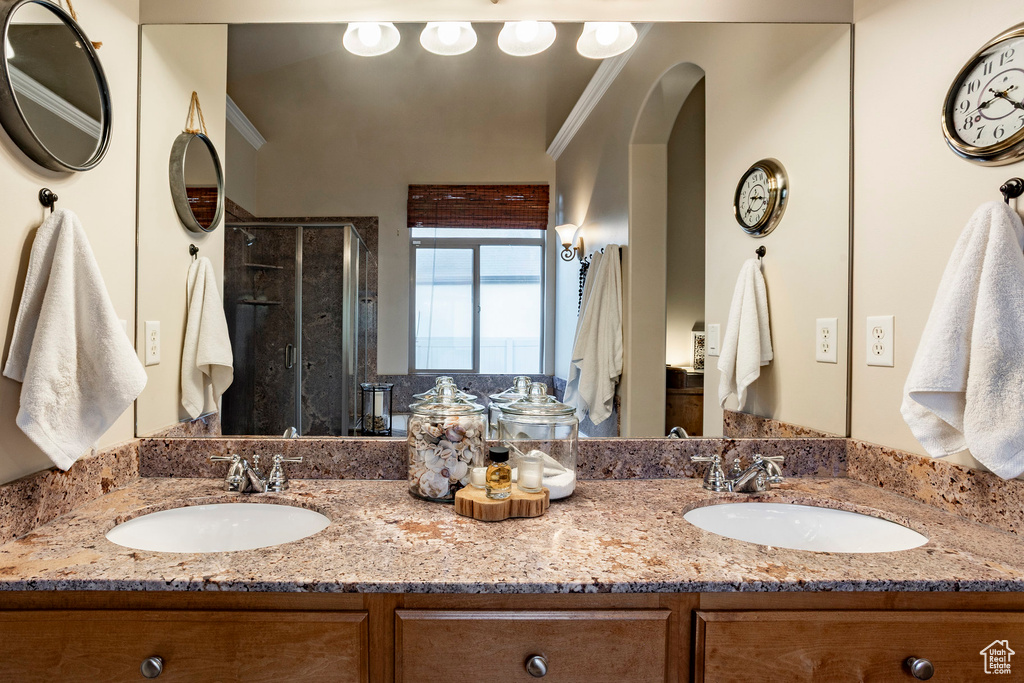 Bathroom with double vanity, a stall shower, and crown molding