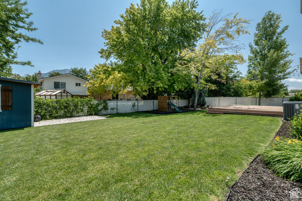 Fenced backyard featuring a playground and a deck