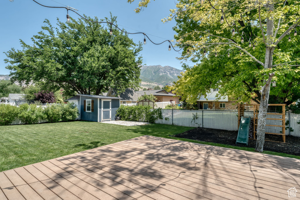 Wooden deck with a fenced backyard, a storage shed, and a mountain view