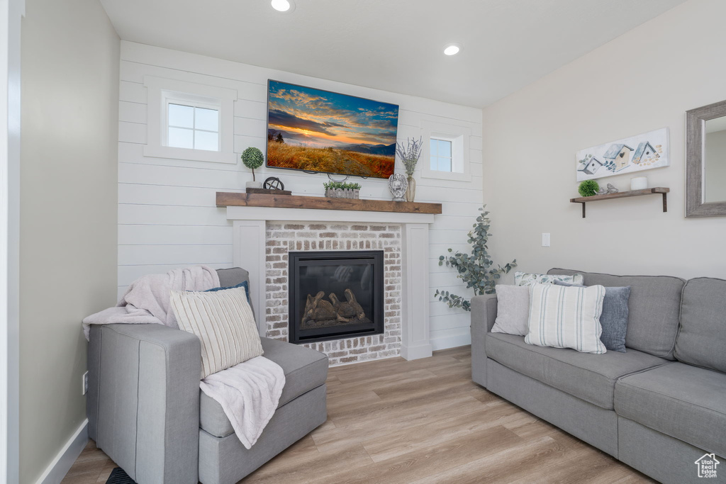 Living room with a brick fireplace, recessed lighting, light wood-style floors, and plenty of natural light