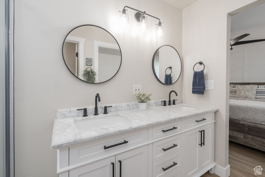 Ensuite bathroom with double vanity, wood finished floors, and ceiling fan