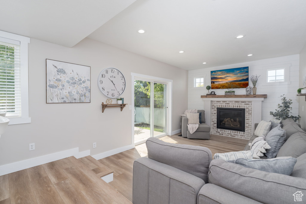 Living area with light wood-style floors, recessed lighting, and a brick fireplace