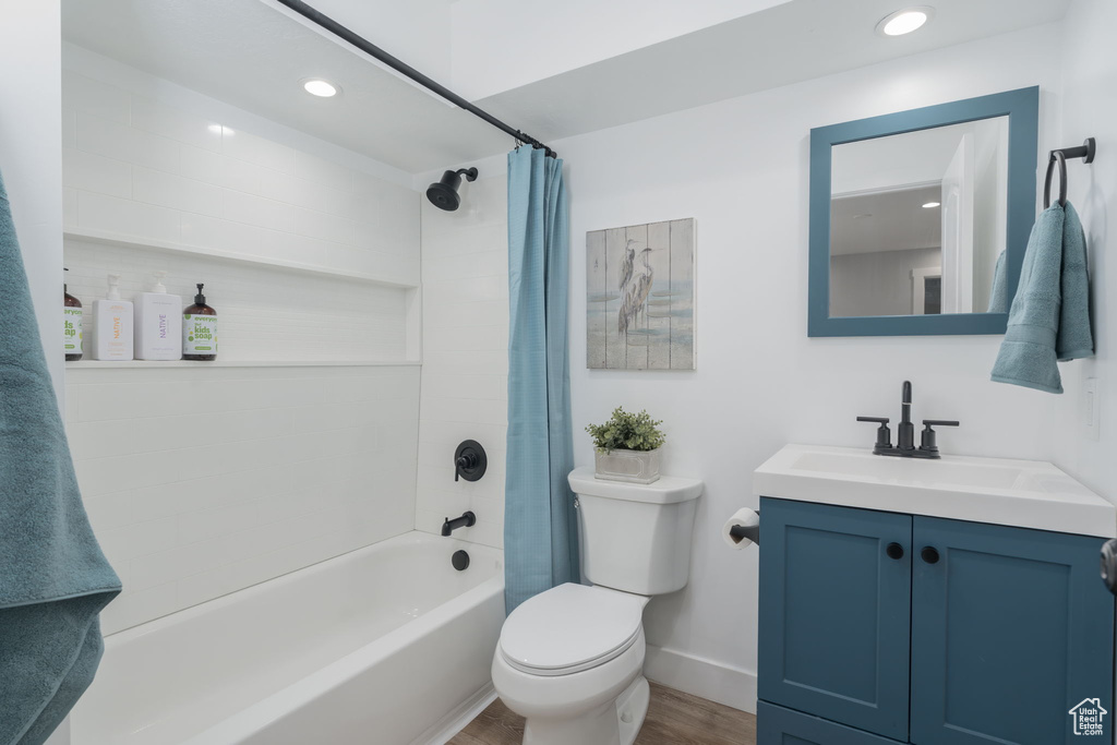 Bathroom featuring vanity, wood finished floors, shower / bath combination with curtain, and recessed lighting