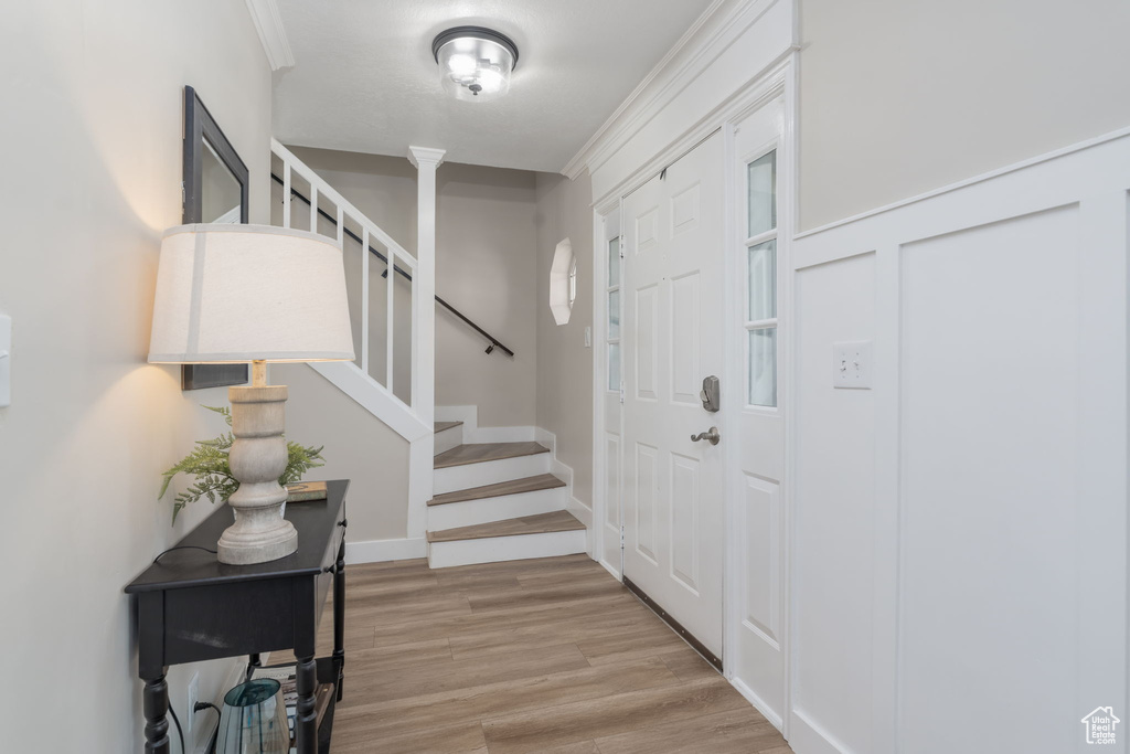 Entryway featuring stairway, wood finished floors, and ornamental molding