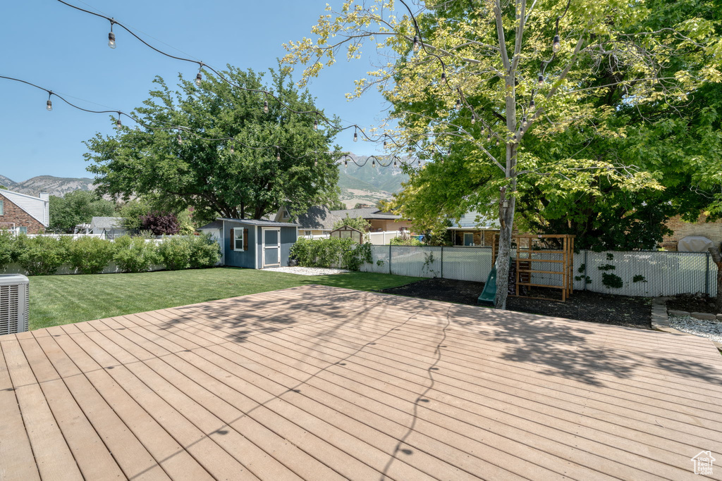 Wooden deck featuring a fenced backyard, a storage unit, and a mountain view
