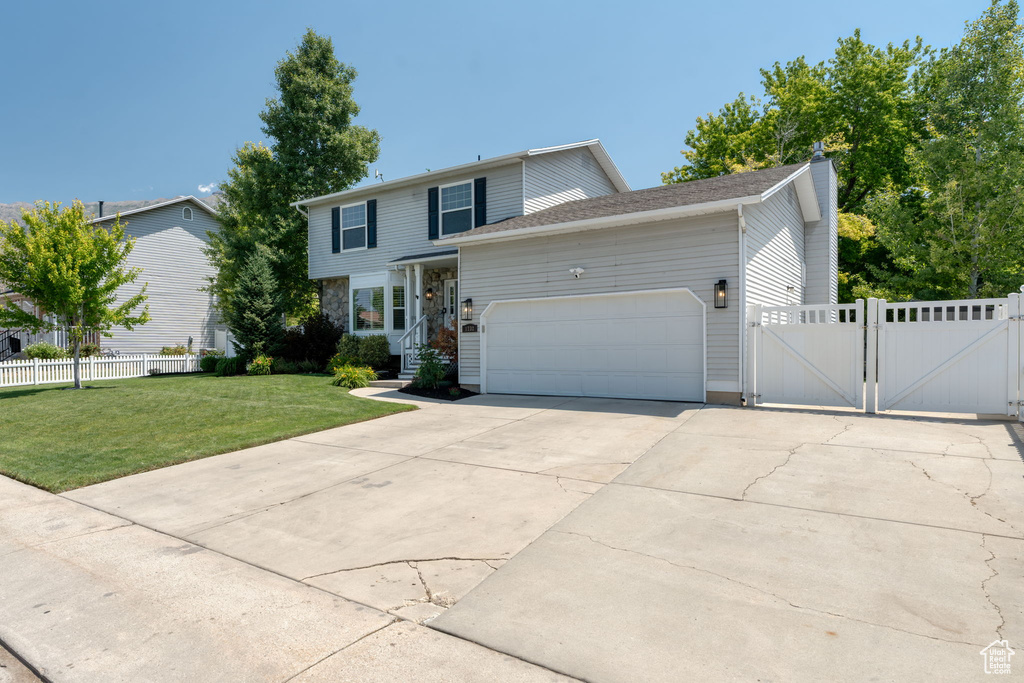 View of front facade with a gate, an attached garage, driveway, and a chimney