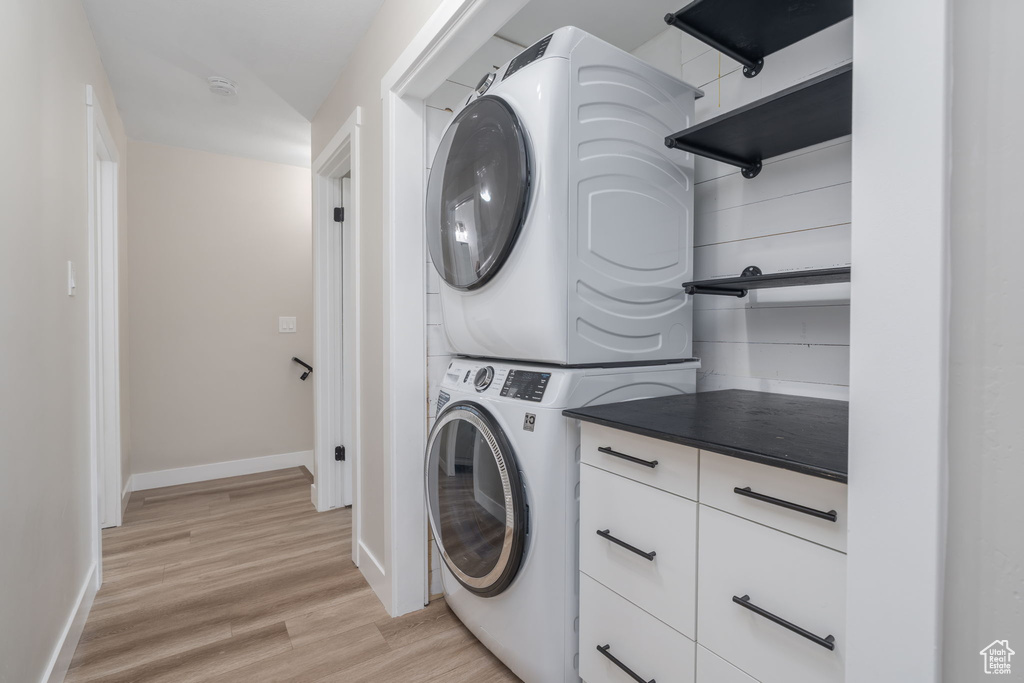 Washroom featuring estacked washer and dryer and light wood-style floors