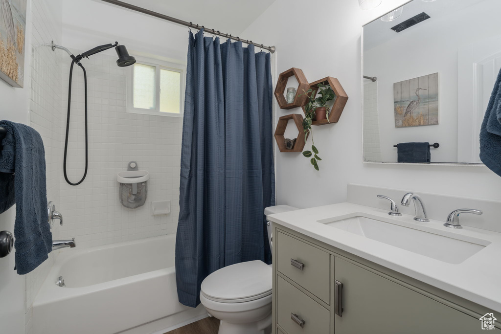 Bathroom with vanity, shower / bath combo with shower curtain, and wood finished floors