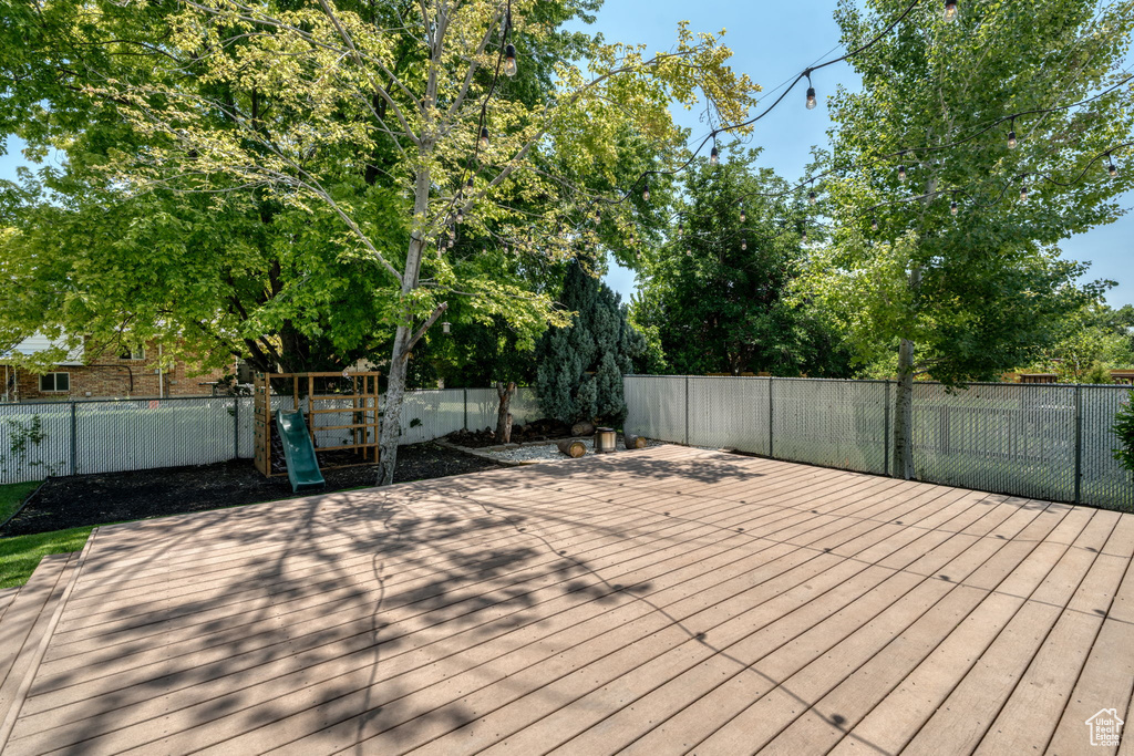 Wooden deck with a playground and a fenced backyard