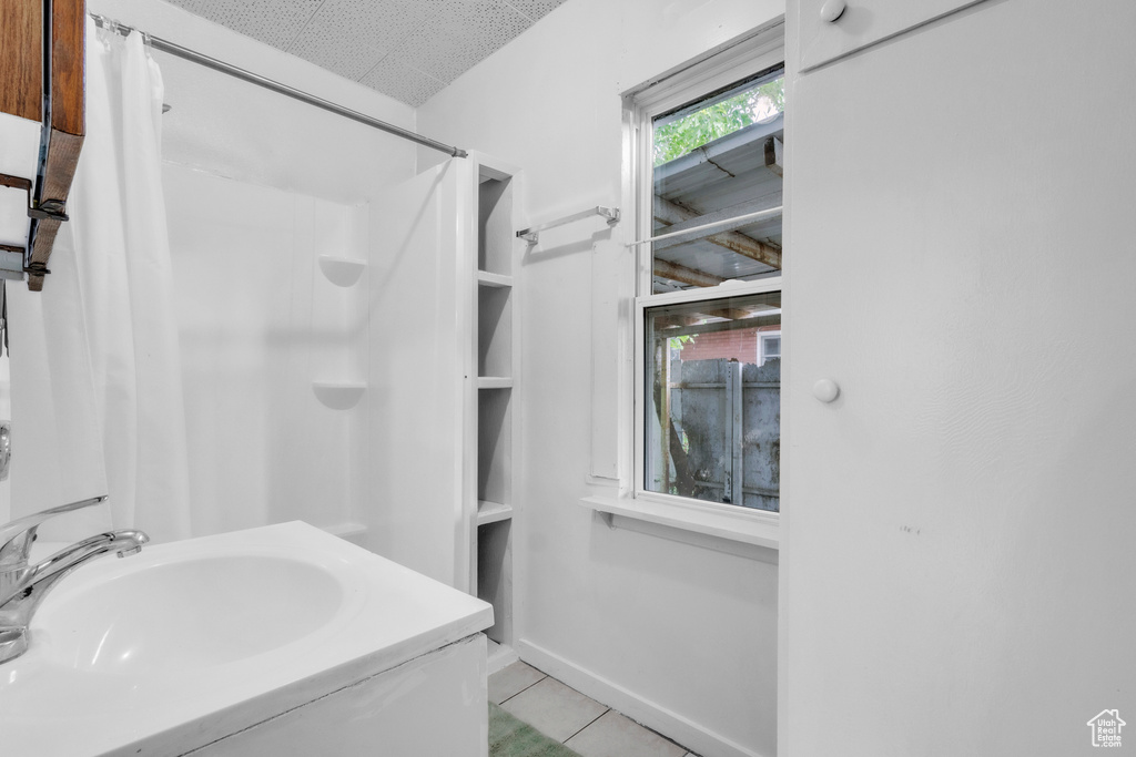 Bathroom featuring tile patterned floors, curtained shower, and vanity