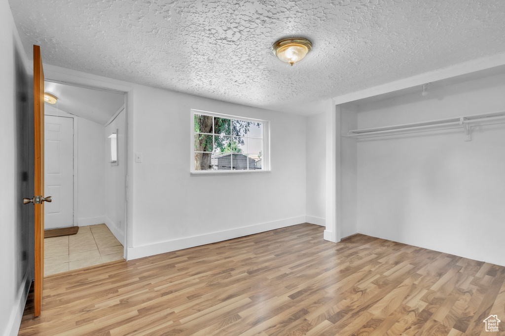 Unfurnished bedroom featuring a textured ceiling, a closet, and wood finished floors