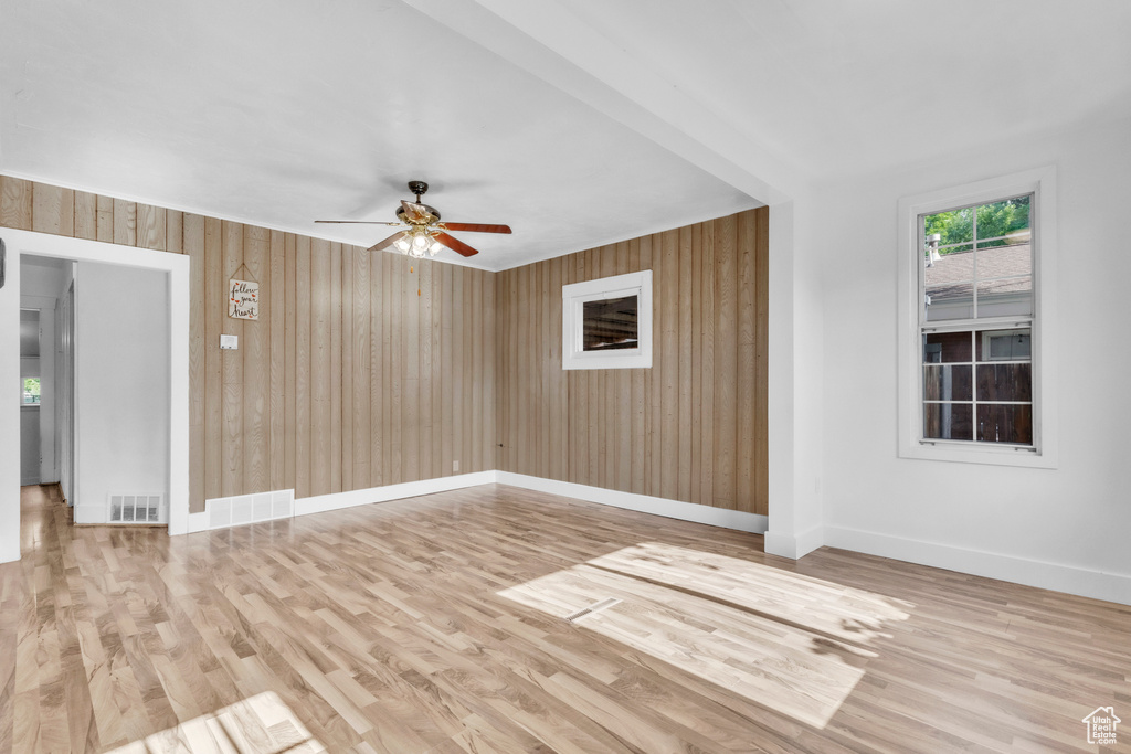 Spare room featuring a ceiling fan, wood walls, and wood finished floors