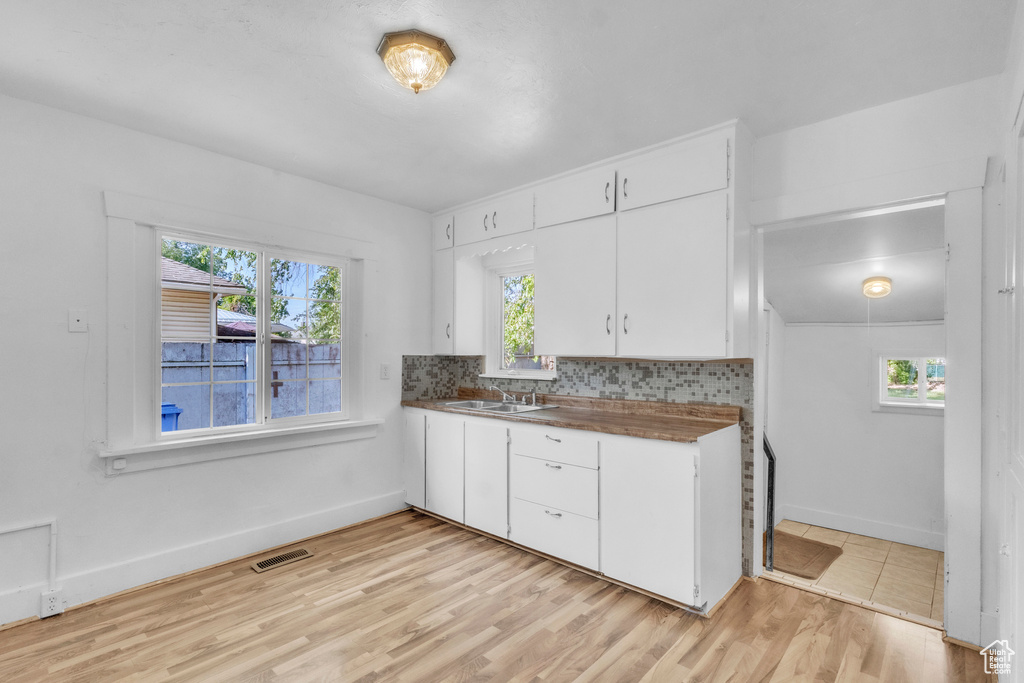 Kitchen with plenty of natural light, white cabinets, and light wood-style floors