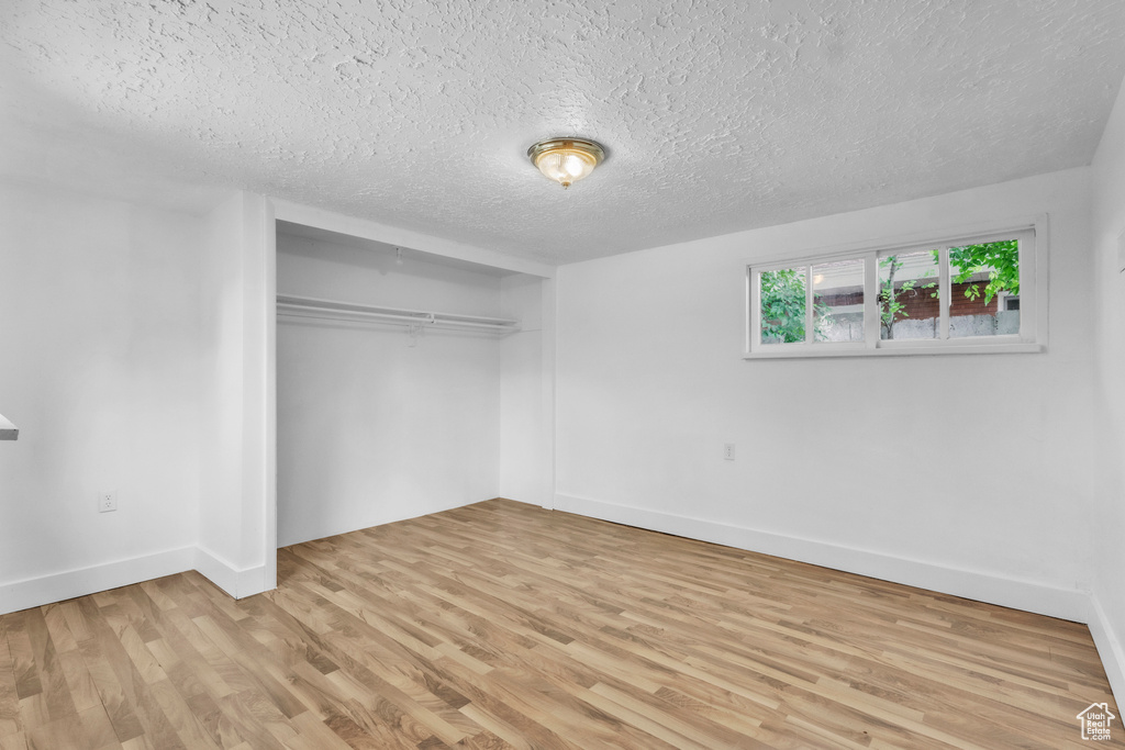 Unfurnished bedroom featuring light wood-style floors, a textured ceiling, and a closet