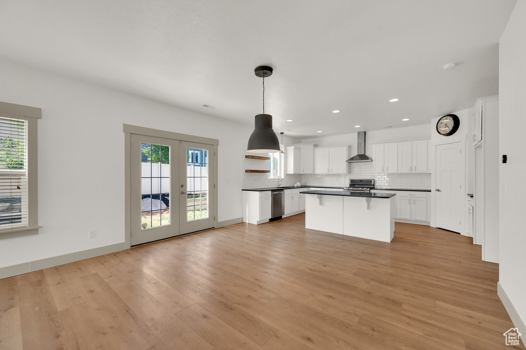 Kitchen with dark countertops, dishwasher, wall chimney range hood, french doors, and backsplash