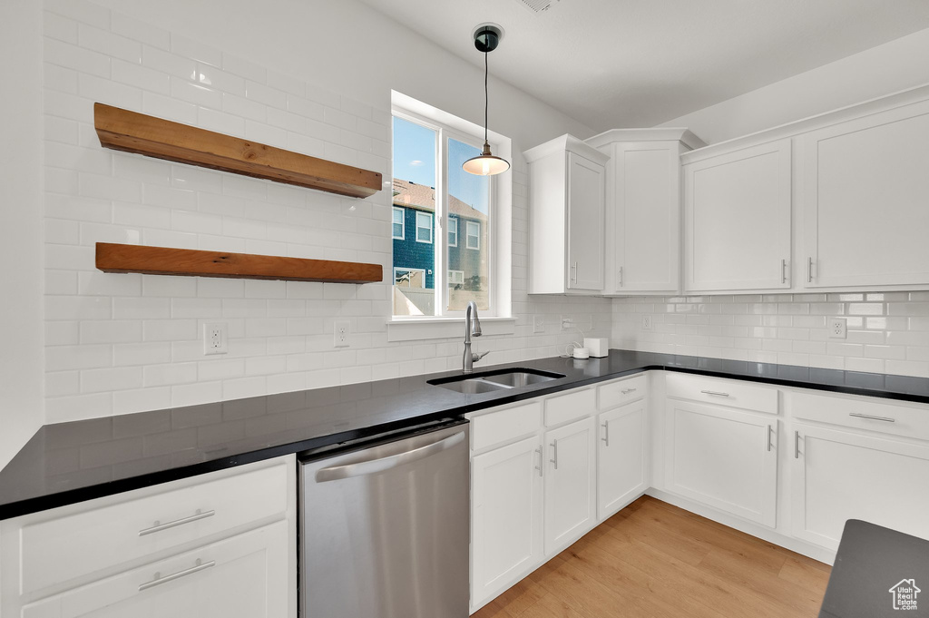 Kitchen with stainless steel dishwasher, open shelves, dark countertops, and white cabinets