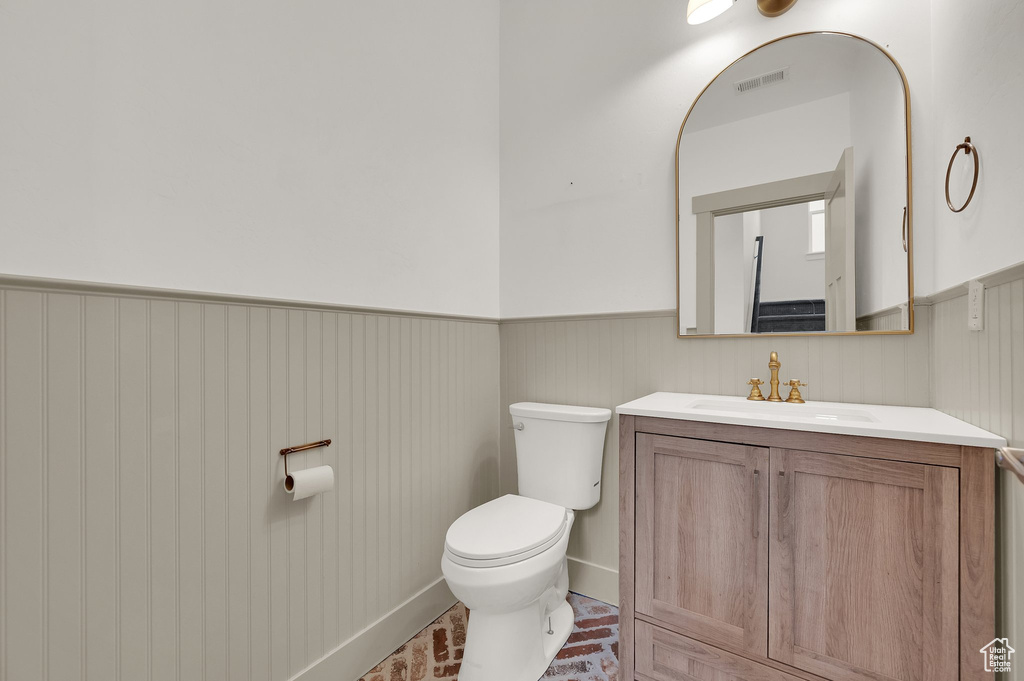 Half bath with a wainscoted wall and vanity