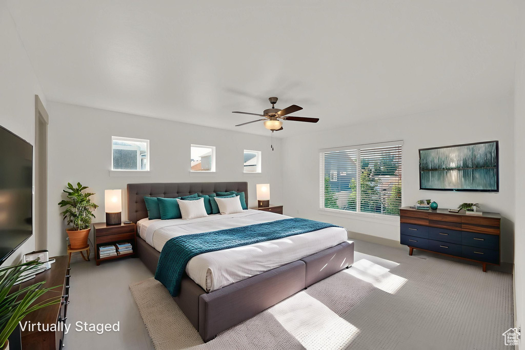 Carpeted bedroom featuring multiple windows and ceiling fan
