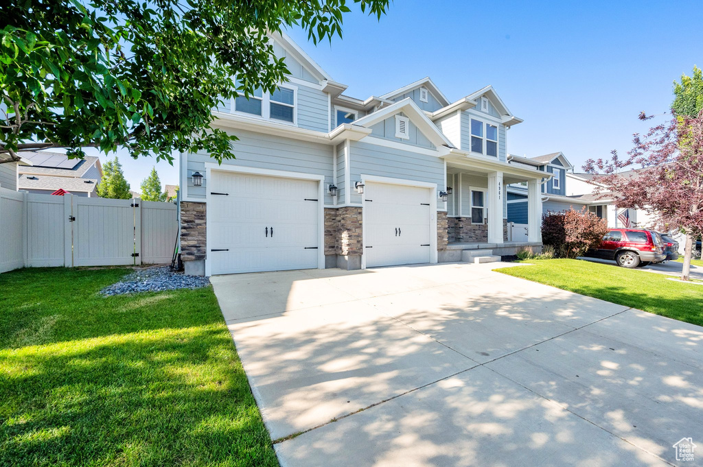 Craftsman inspired home featuring a gate, concrete driveway, an attached garage, and stone siding