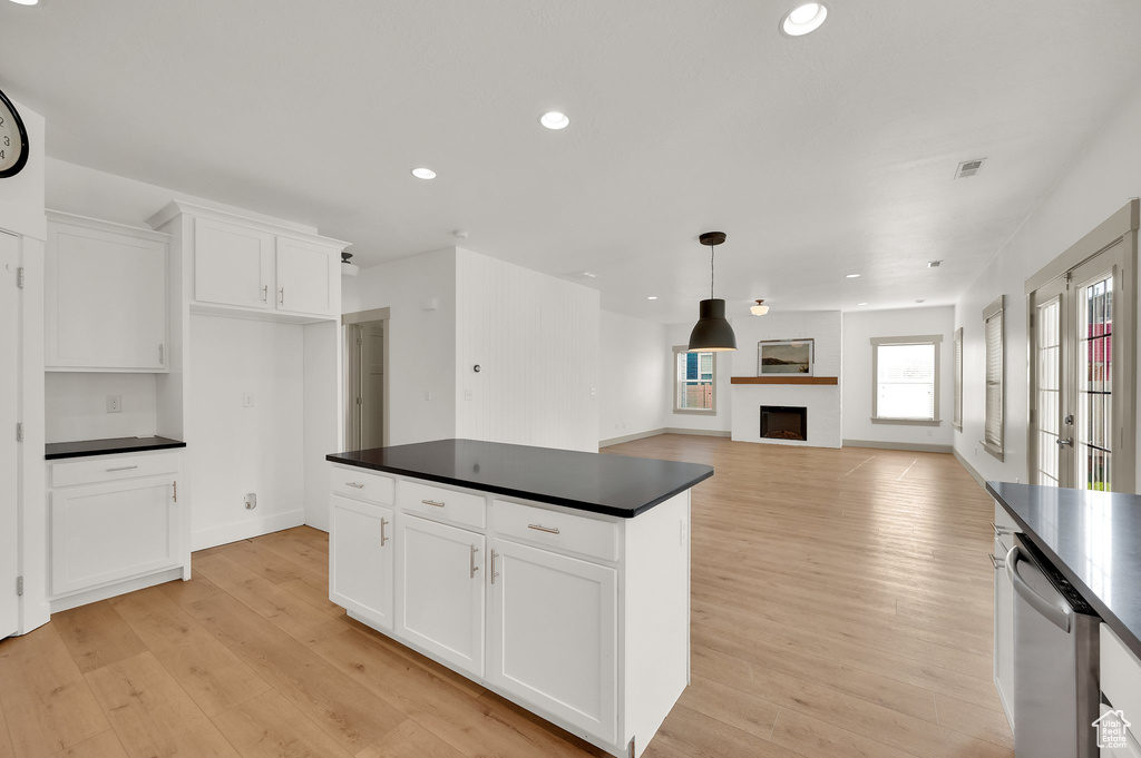 Kitchen with dark countertops, stainless steel dishwasher, light wood-style flooring, white cabinets, and recessed lighting