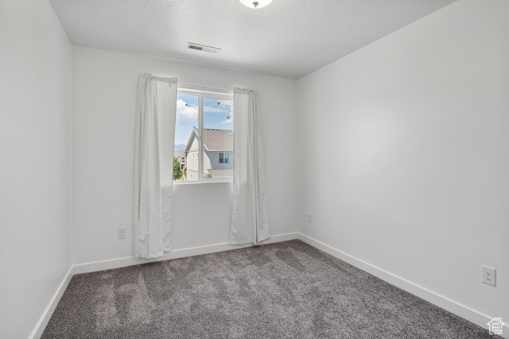 Carpeted empty room featuring baseboards and a textured ceiling