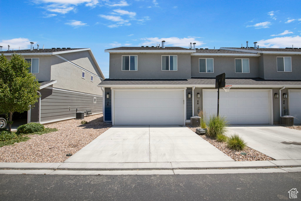 Traditional home featuring a garage, concrete driveway, and stucco siding