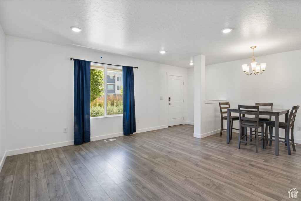 Dining space with a chandelier, wood finished floors, a textured ceiling, and recessed lighting