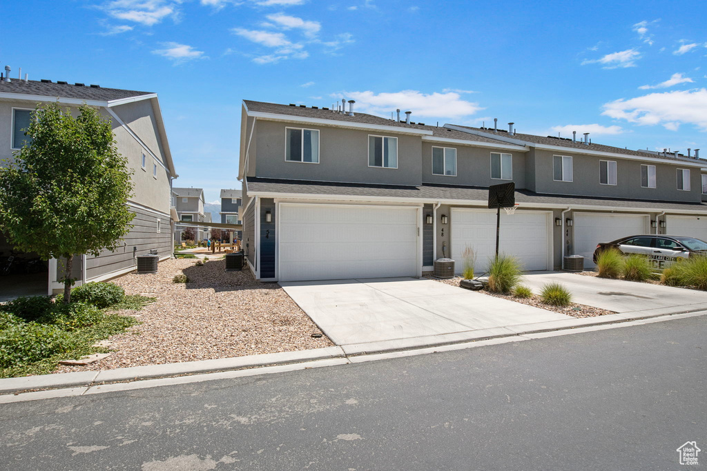 View of front facade featuring a garage, concrete driveway, and stucco siding