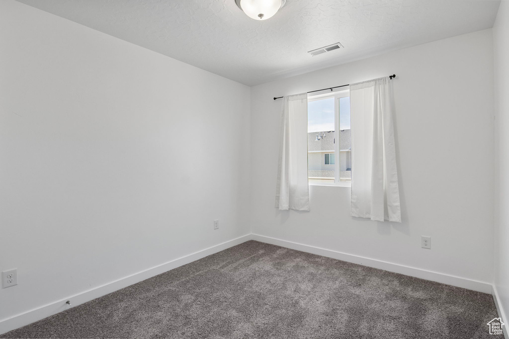 Unfurnished room featuring dark colored carpet and baseboards