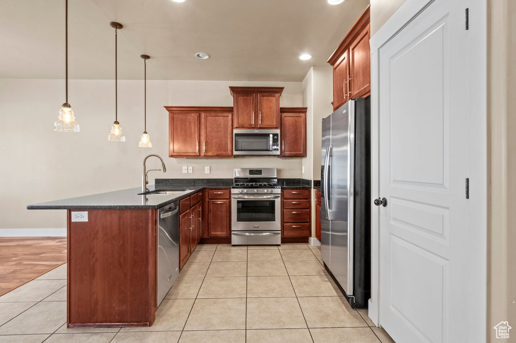 Kitchen with stainless steel appliances, a peninsula, light tile patterned floors, recessed lighting, and hanging light fixtures