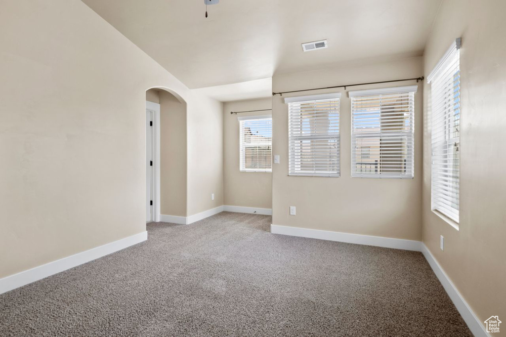 Empty room with arched walkways and light carpet