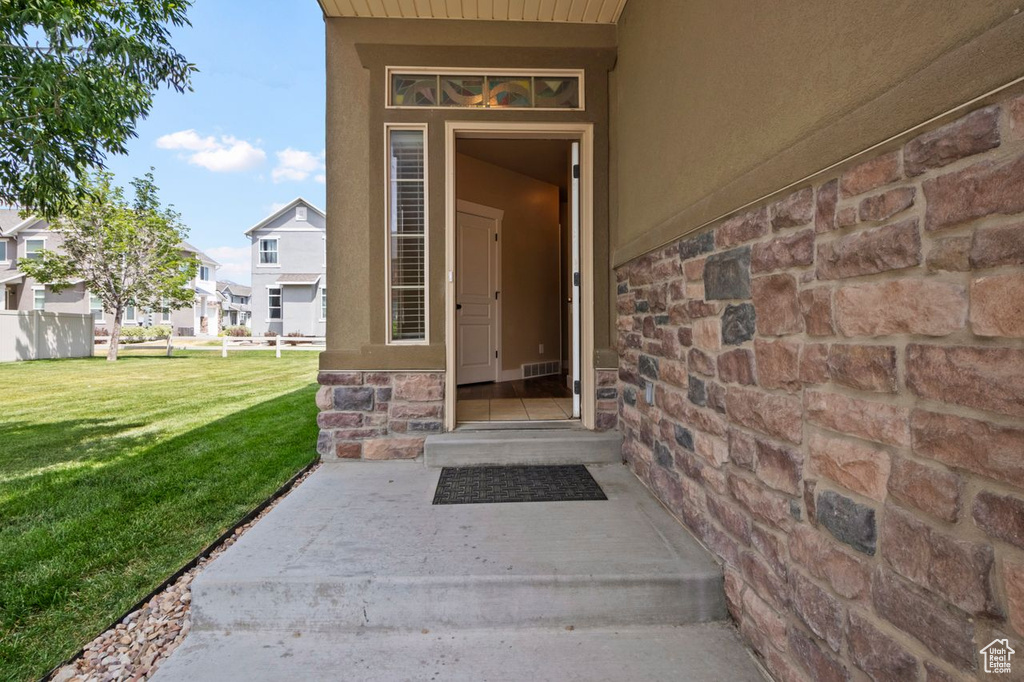 Property entrance with stone siding, a yard, stucco siding, and a residential view